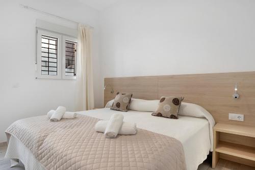 a white bedroom with a large bed with white sheets at Apartamento Guzmán A in Barbate