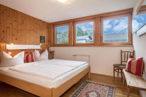 a bedroom with a large bed and windows at Försterhaus Wohnung Dachgeschoss in Egg