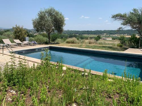 a swimming pool in a field with two chairs next to it at Ferme du Luberon in Mane
