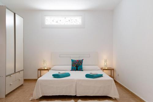a white bedroom with a large bed with blue pillows at Casa Rosi in Tinajo