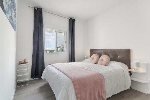 ein weißes Schlafzimmer mit einem großen Bett und rosa Kissen in der Unterkunft Stevier in Icod de los Vinos
