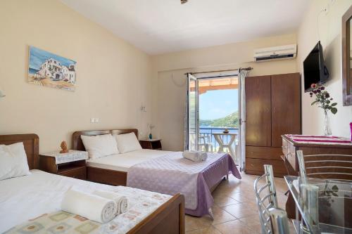 a hotel room with two beds and a balcony at Vardia studio A in Mikros Gialos