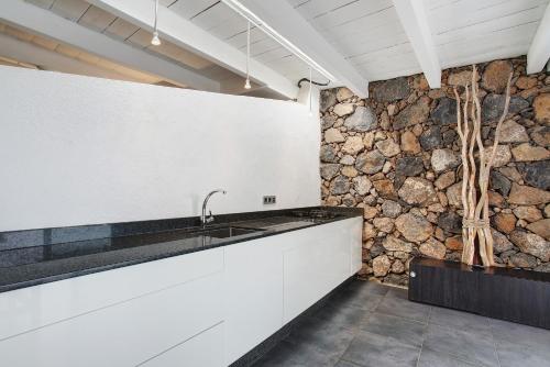 a kitchen with a sink and a stone wall at La Bodeguita House in Haría