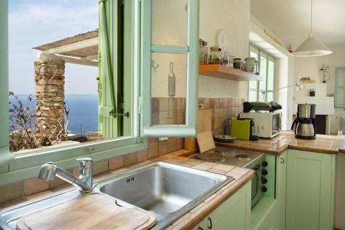 a kitchen with a sink and a window at Casa Xyla-sunset view villa in Melissaki