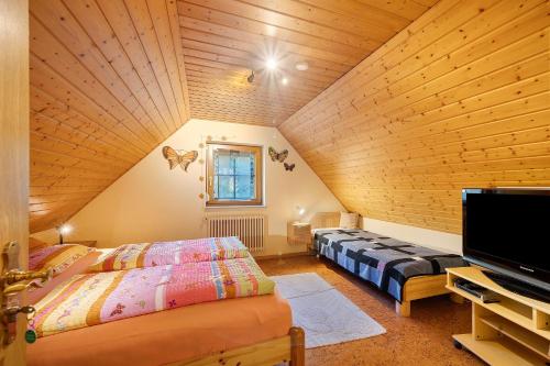 a attic bedroom with two beds and a flat screen tv at Ferienwohnungen Müller in Haslach im Kinzigtal