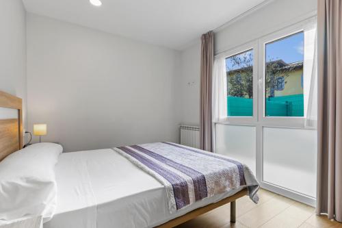 a white bedroom with a bed and a window at 4 Jardin- Puerto Chico in Llanes