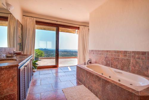 a large bathroom with a tub and a large window at Sa Muntanya panorama in Santa Eularia des Riu