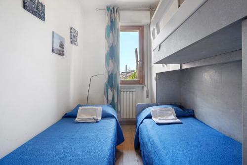 two beds in a room with blue sheets and a window at Coral House Viareggio in Viareggio