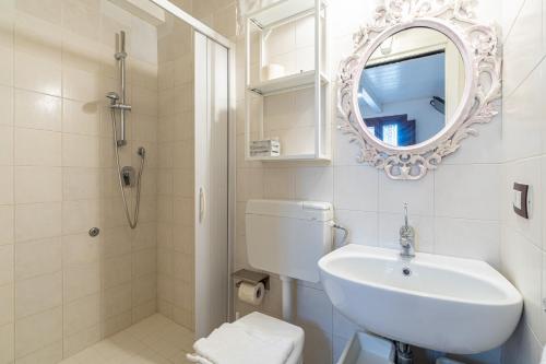 a white bathroom with a sink and a mirror at Casamari nel centro di Marzamemi in Marzamemi