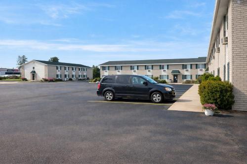 a black van parked in a parking lot in front of a building at Iron Mountain Inn & Suites MI US 2 in Iron Mountain