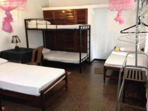 a room with three bunk beds and a table at Drop Hostel in Kandy