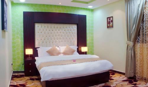 a bedroom with a large bed with green walls at Diyafat Al Saada Serviced Apartments - Ishbillia in Riyadh