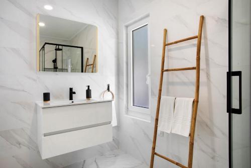 a white bathroom with a sink and a mirror at Casa da Vinha in Óbidos