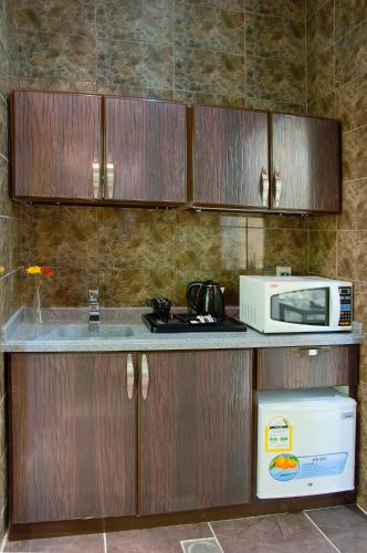 a kitchen with a counter with a microwave and a refrigerator at Diyafat Al Saada Serviced Apartments - Ishbillia in Riyadh