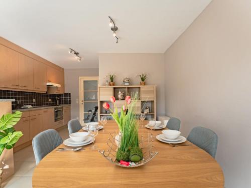 a dining room with a wooden table with flowers on it at Apartment Zandloper with balcony by Interhome in Bredene