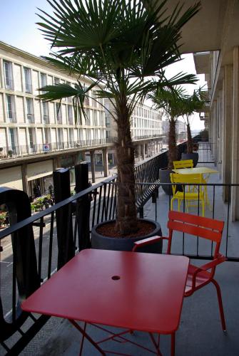 a red table and chairs on a balcony with a palm tree at ibis Styles Le Havre Centre in Le Havre