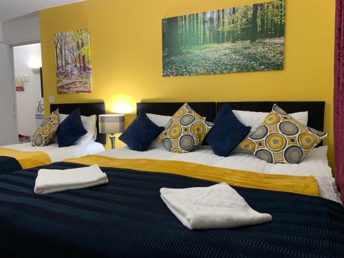 a bedroom with two beds with blue and yellow pillows at 2 Bedrooms Modern Apartment, Lounge, Full Kitchen, Balcony, 5 minutes Stratford Station in London