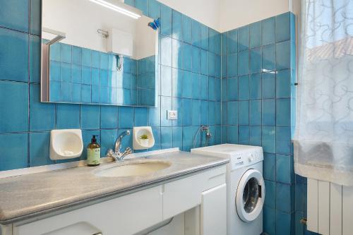 a blue tiled bathroom with a sink and a washing machine at Il Noce - vicino Chiavari in Leivi
