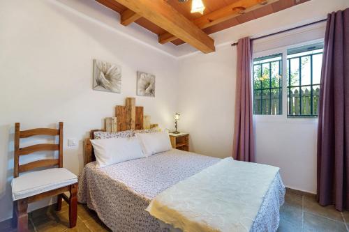a bedroom with a bed and a chair and a window at Casa Andrea in Barbate
