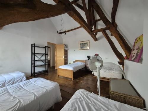 a attic bedroom with two beds and a fan at Maison de Vacances Chez La Prade in Salagnac