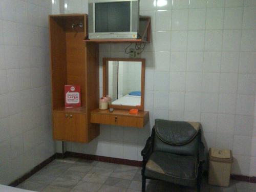 a room with a tv and a chair and a mirror at Hotel Pinangsia in Jakarta