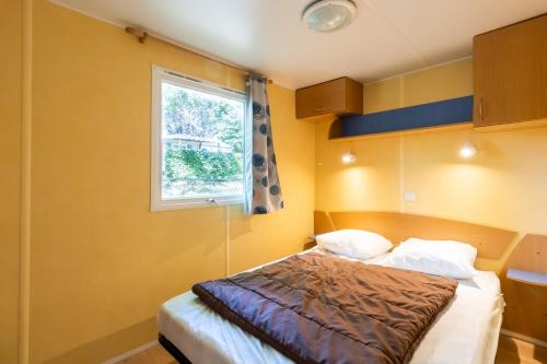a bedroom with a bed and a window at Mobilhome La Clairière in Saint-Pompont
