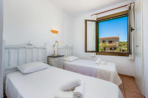 two beds in a room with a window at Ran de Mar in Son Serra de Marina