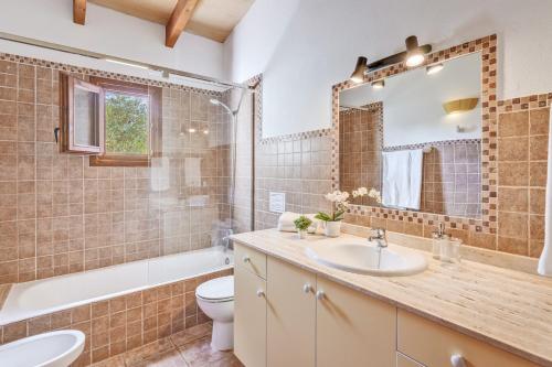 a bathroom with a sink and a toilet and a mirror at Villa Joana in Pollença