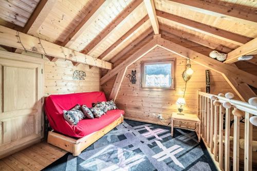 a red couch in the corner of a wooden room at Chalet 6p Confort - Le bouvreuil in Verchaix