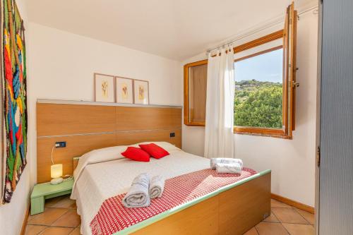 a bedroom with a bed with red pillows and a window at 4 Appartamento Cala Brandinchi in San Teodoro