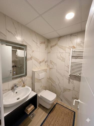 a bathroom with a sink and a toilet and a mirror at Emerald Luxury Apartments in Skopje