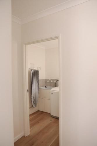 a white kitchen with a sink and a refrigerator at Kawa House in Kalbarri