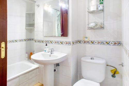 a white bathroom with a toilet and a sink at Playa Sardina in Gáldar