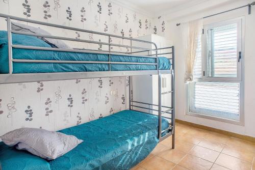 a bedroom with two bunk beds with blue sheets at Playa Sardina in Gáldar