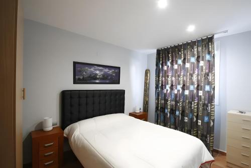 a bedroom with a bed with a black headboard and a window at Villa María Magdalena in Cambrils