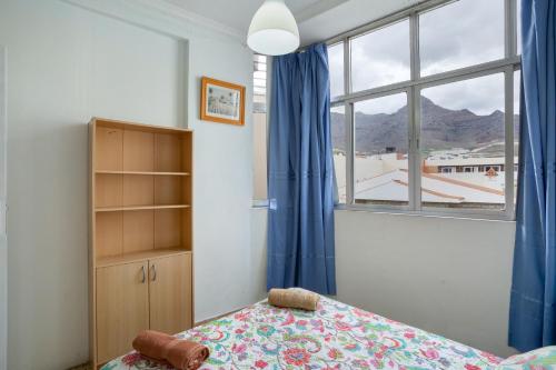 a bedroom with a bed and a window with blue curtains at Apartamento karla in San Nicolás