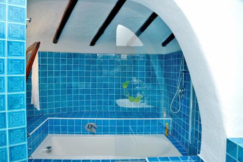 a blue tiled bathroom with a tub and a sink at Villa Ibiscus in Porto Rafael