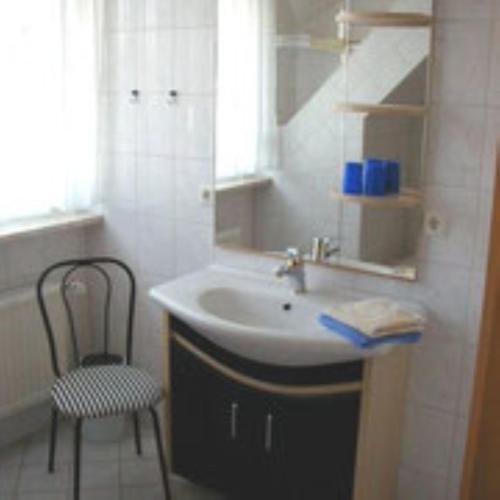 a bathroom with a sink and a chair and a mirror at Haus Lechner in Cuxhaven