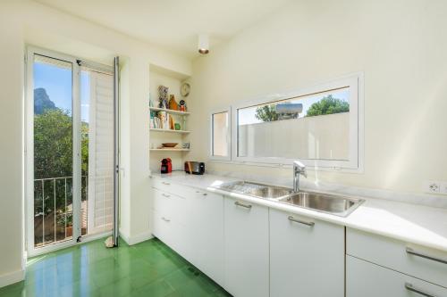 a white kitchen with a sink and a window at Villa Mercedes in Artá