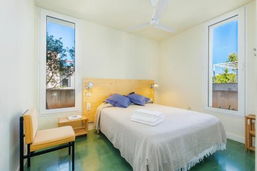 a bedroom with a large bed and two windows at Villa Mercedes in Artá