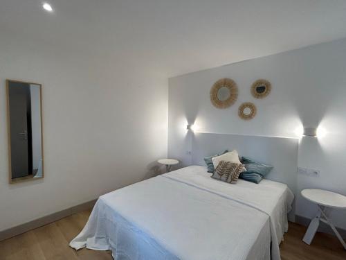 a white bedroom with a bed and a mirror at Au p'tit Colombier in Hillion