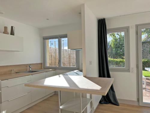 a kitchen with white cabinets and a table and windows at Au p'tit Colombier in Hillion