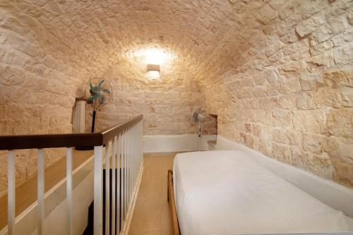 a small room with a bed in a stone wall at La Dimora dello Zio, with pool in Ostuni