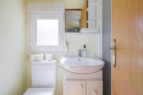 a bathroom with a sink and a toilet and a window at Bungalow A6 in Pontevedra