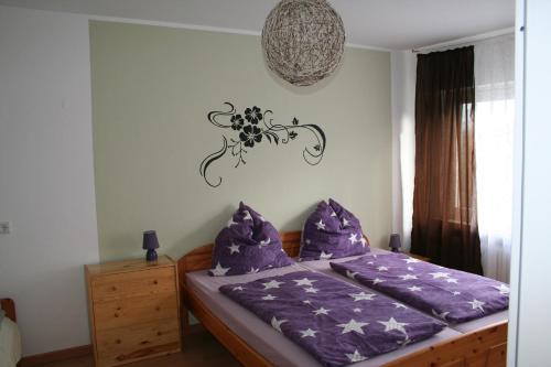 a bedroom with a bed with purple sheets and a chandelier at Ferienwohnung Sammet in Brilon