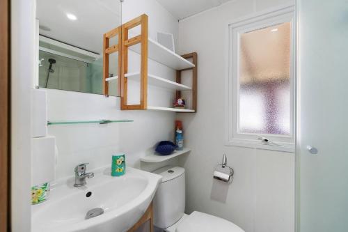 a white bathroom with a toilet and a sink at Mobilehome 5 personnes in Les Mathes