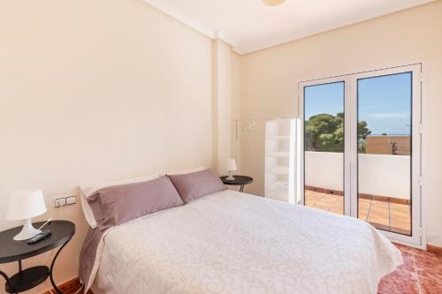a white bedroom with a bed and a balcony at Primera Planta in Cartagena