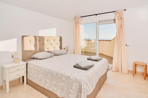 a white bedroom with a bed and a window at Beautiful Penthouse in Torrox Costa