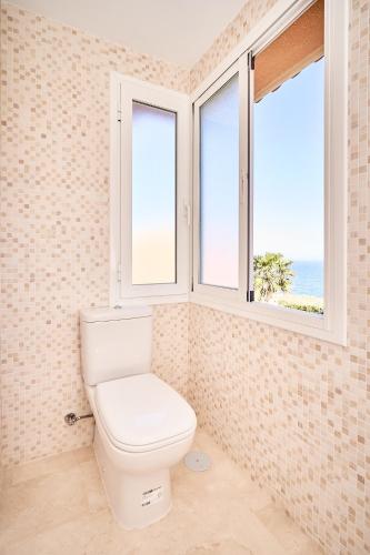 a bathroom with a toilet and two windows at Beautiful Penthouse in Torrox Costa