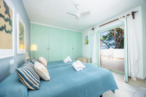 a blue bed in a room with a sliding glass door at Can Botana 9 in Cala de Sant Vicenc
